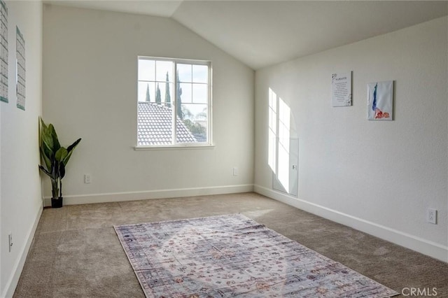 carpeted spare room featuring baseboards, a healthy amount of sunlight, and vaulted ceiling