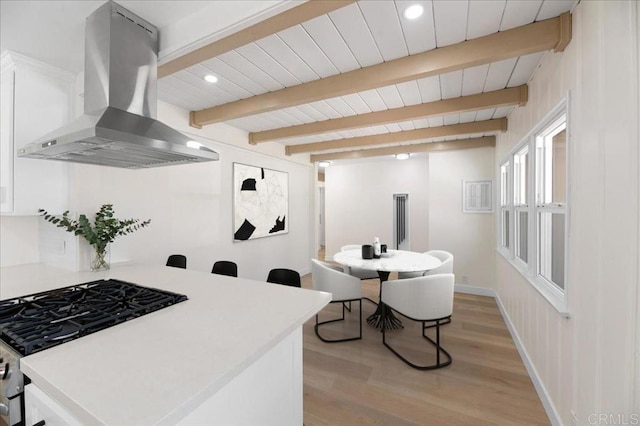 kitchen featuring island exhaust hood, stainless steel gas stove, light wood-style floors, light countertops, and white cabinets