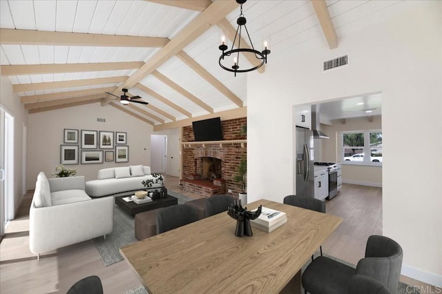 living room with wood finished floors, a brick fireplace, a ceiling fan, a chandelier, and baseboards