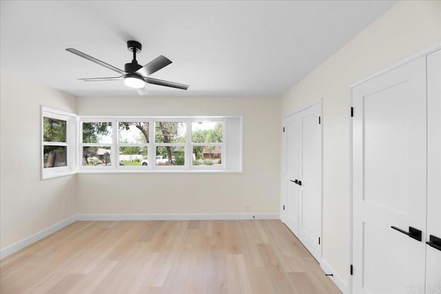 unfurnished bedroom with light wood-style flooring, baseboards, and a ceiling fan