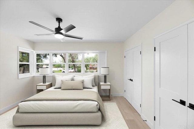bedroom with light wood-type flooring, baseboards, and a ceiling fan