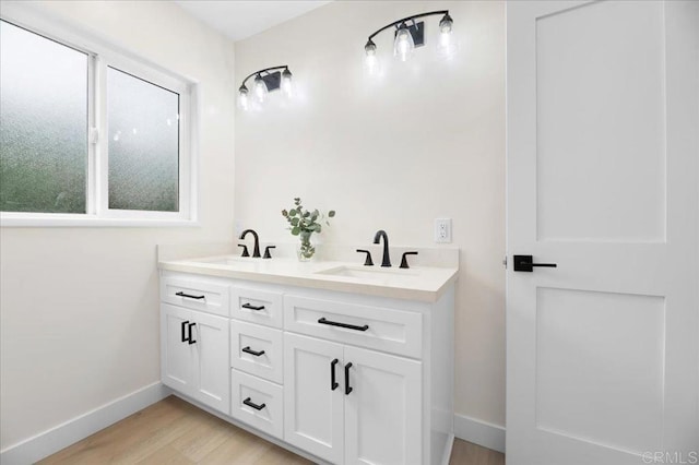 bathroom with baseboards, wood finished floors, and double vanity