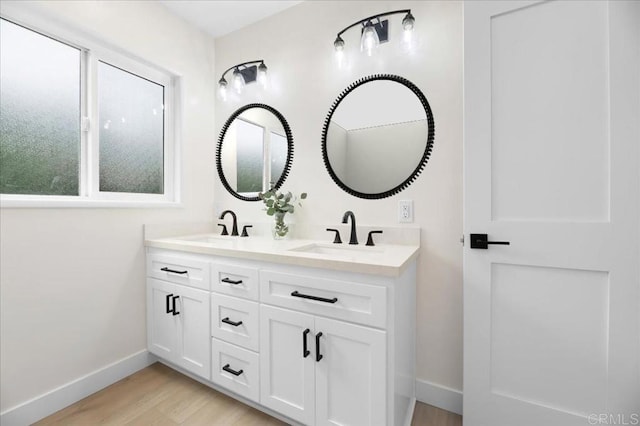 full bathroom with baseboards, wood finished floors, and double vanity