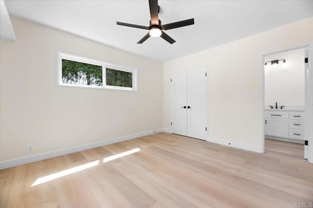 unfurnished bedroom with light wood-style floors, baseboards, a sink, and a closet