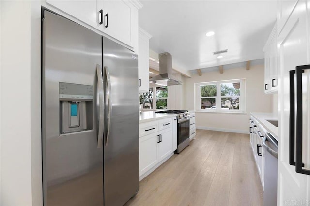 kitchen with stainless steel appliances, island range hood, light wood finished floors, white cabinets, and light countertops