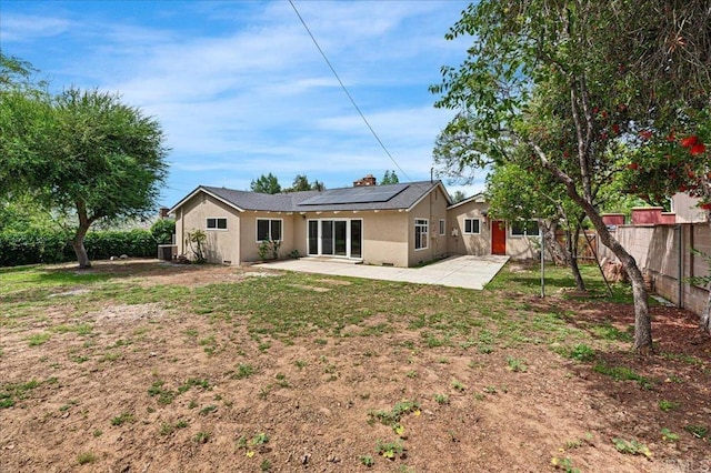 back of house featuring a patio area, solar panels, stucco siding, and central AC