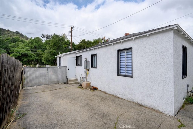 view of side of property with entry steps, stucco siding, and fence