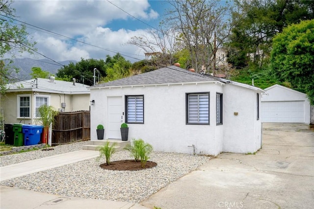 view of home's exterior featuring stucco siding, fence, an outbuilding, a detached garage, and a mountain view