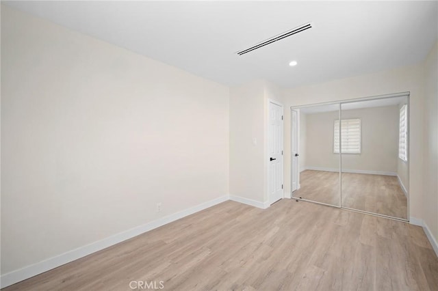 unfurnished bedroom featuring visible vents, recessed lighting, a closet, baseboards, and light wood-type flooring