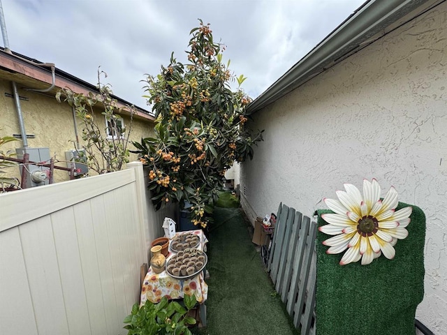 view of side of home featuring stucco siding and fence