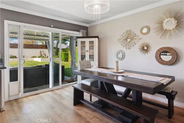 dining area featuring ornamental molding and light wood finished floors