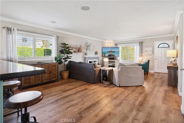 living room with crown molding, baseboards, a fireplace, and light wood-style floors