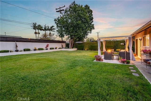 yard at dusk with a fenced backyard, a patio, and outdoor lounge area