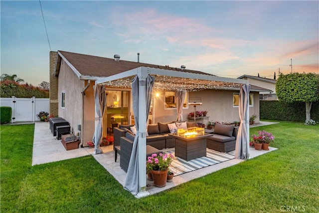 back of property with an outdoor living space with a fire pit, stucco siding, a gate, a patio, and a yard