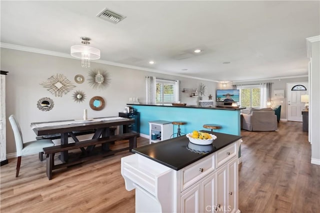 kitchen featuring visible vents, ornamental molding, a wealth of natural light, and dark countertops