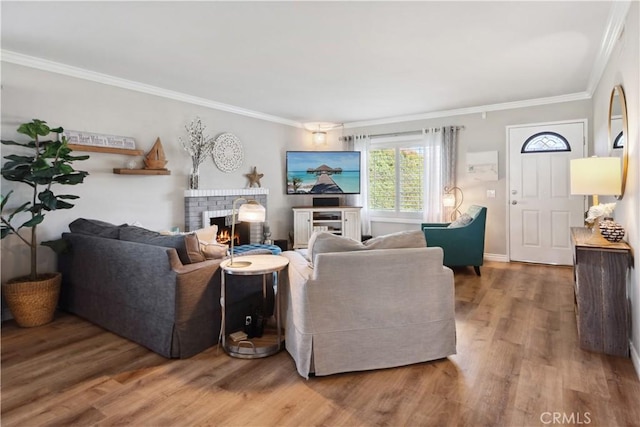 living area with a brick fireplace, baseboards, ornamental molding, and wood finished floors