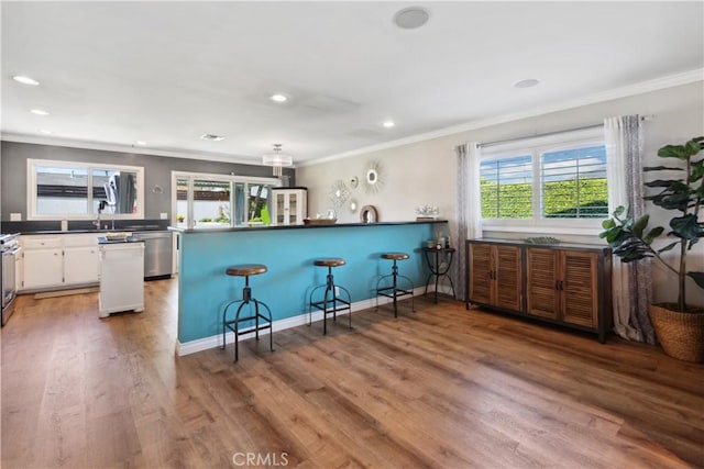 kitchen featuring crown molding, white cabinets, a peninsula, stainless steel appliances, and light wood-style flooring