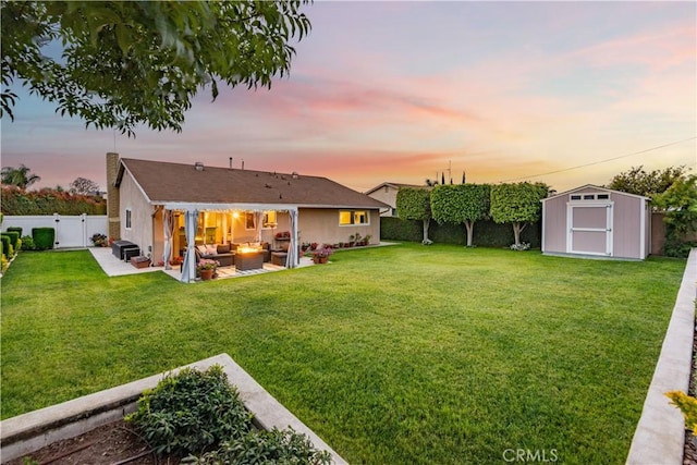 yard at dusk with a fenced backyard, an outdoor living space, an outbuilding, a patio area, and a storage shed