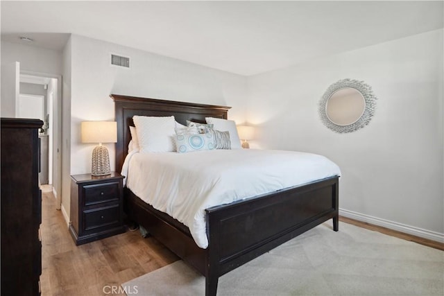 bedroom featuring visible vents, baseboards, and wood finished floors