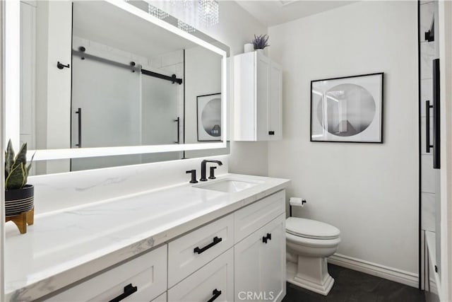 bathroom with vanity, baseboards, a stall shower, and toilet
