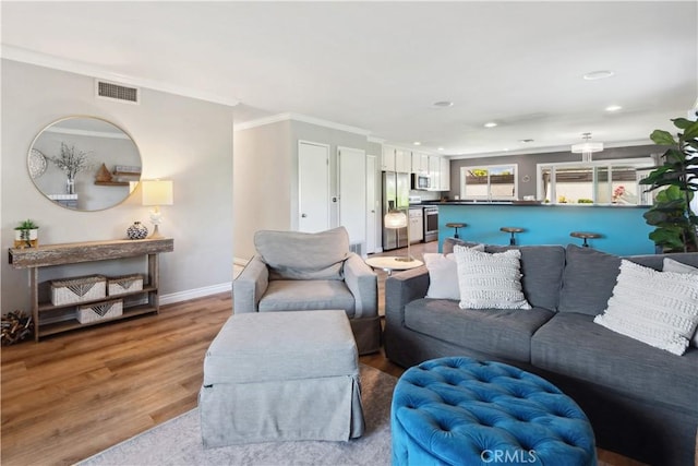 living area with crown molding, recessed lighting, baseboards, light wood-type flooring, and visible vents