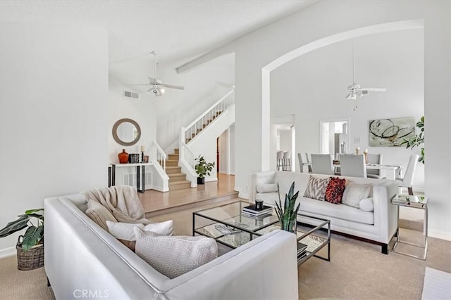 carpeted living room with stairway, high vaulted ceiling, and a ceiling fan