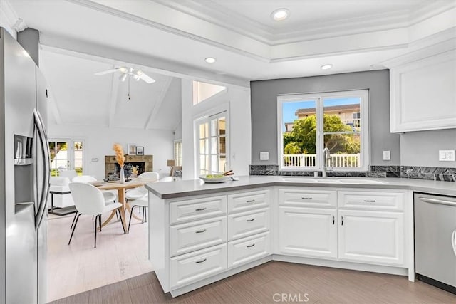 kitchen featuring appliances with stainless steel finishes, a sink, white cabinets, a peninsula, and recessed lighting