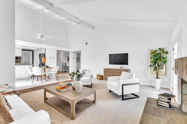 living area with rail lighting, ceiling fan, beam ceiling, and high vaulted ceiling