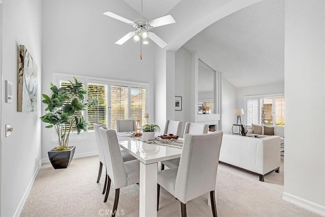 dining room with light colored carpet, baseboards, and high vaulted ceiling