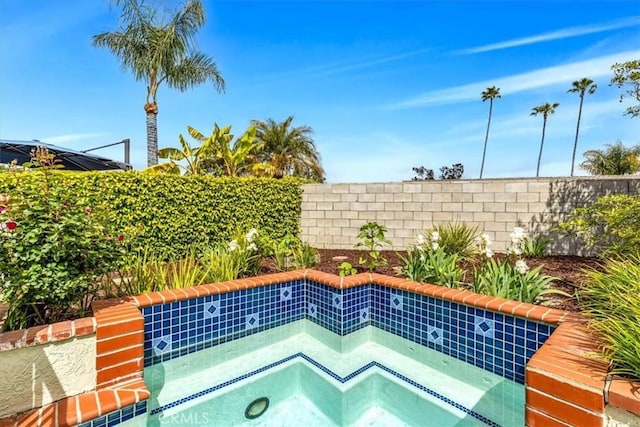 view of pool featuring an in ground hot tub and fence