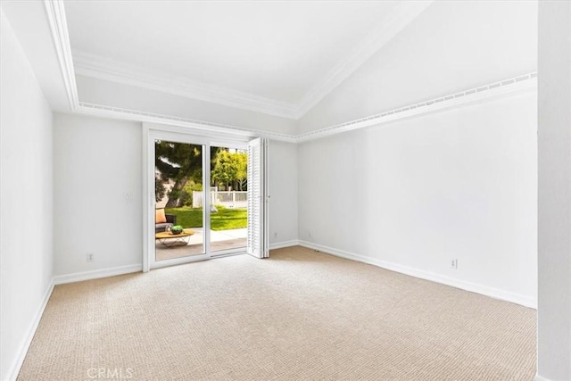 carpeted empty room featuring crown molding, baseboards, and vaulted ceiling