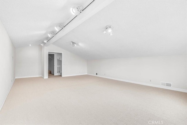 bonus room with baseboards, lofted ceiling, light colored carpet, and visible vents