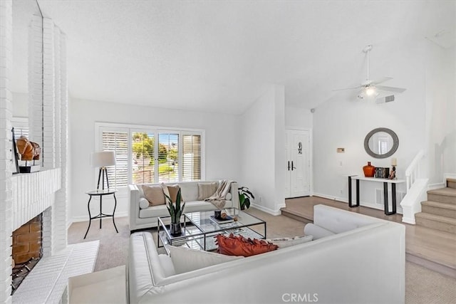 living area featuring carpet, vaulted ceiling, a fireplace, and stairway
