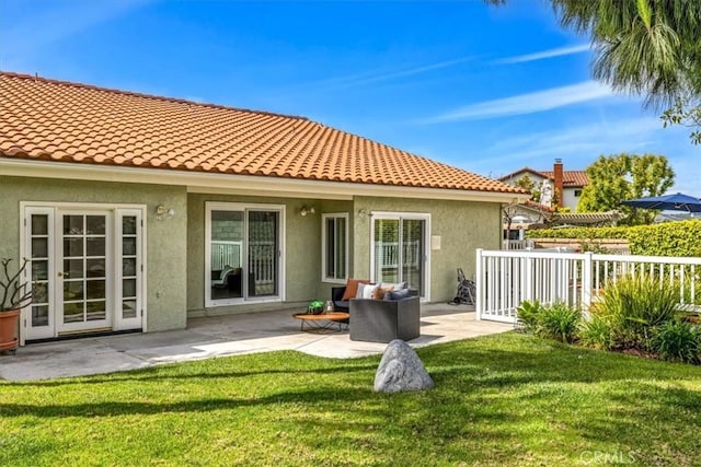 back of house with a patio area, stucco siding, a yard, and a tile roof
