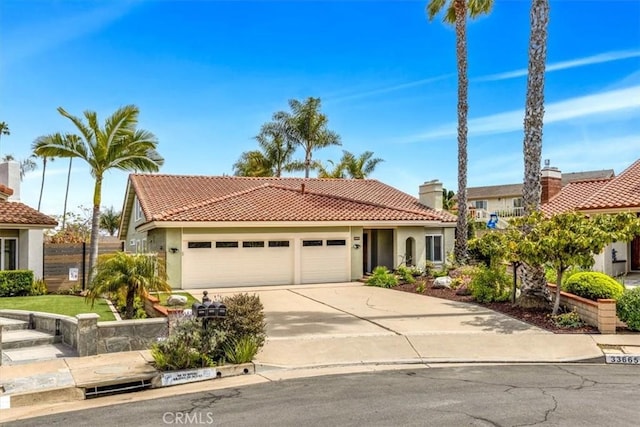 mediterranean / spanish-style home featuring an attached garage, stucco siding, a tiled roof, and concrete driveway