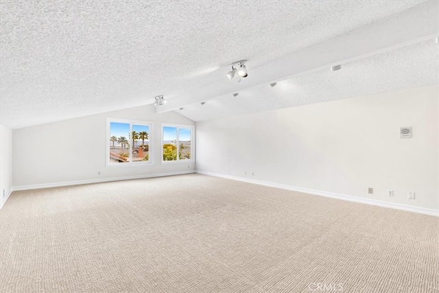 interior space with baseboards, lofted ceiling with beams, a textured ceiling, and light carpet
