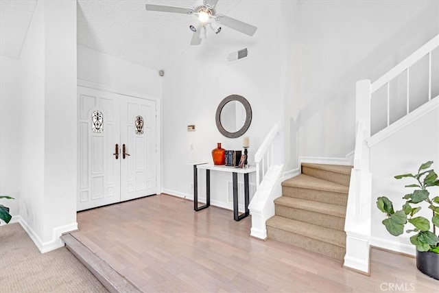 foyer entrance featuring ceiling fan, visible vents, baseboards, and stairway