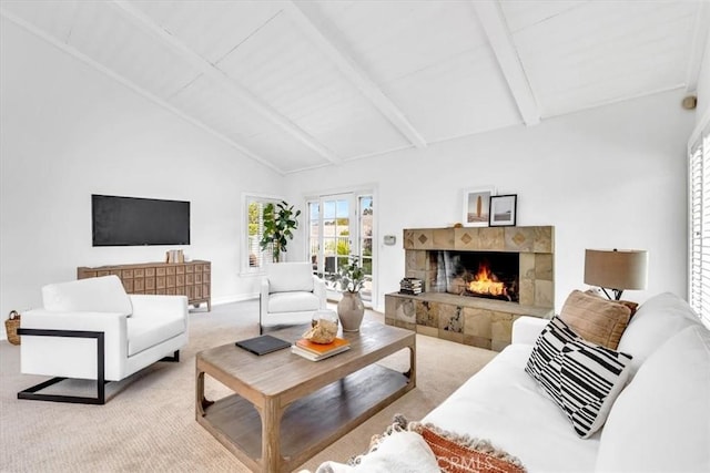 living area with baseboards, lofted ceiling with beams, light carpet, and a tile fireplace