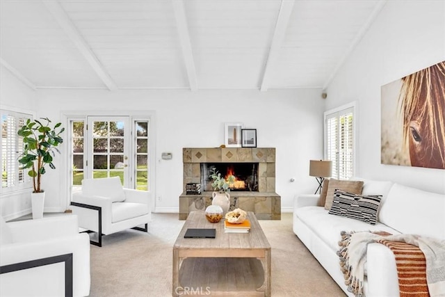 living room with a tiled fireplace, baseboards, vaulted ceiling with beams, and light carpet