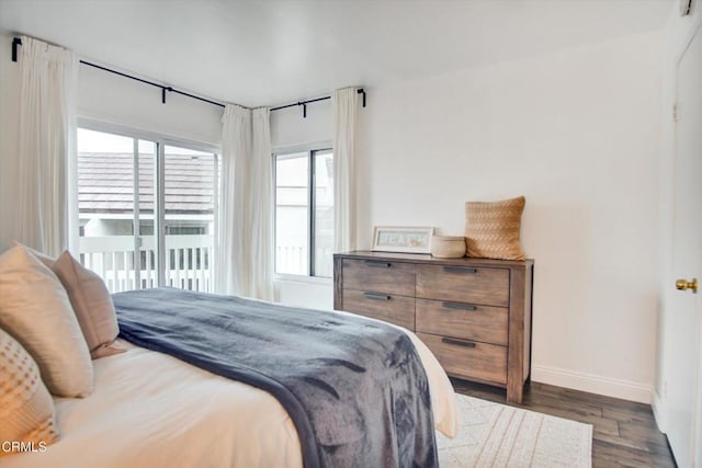 bedroom featuring baseboards, wood finished floors, and access to exterior