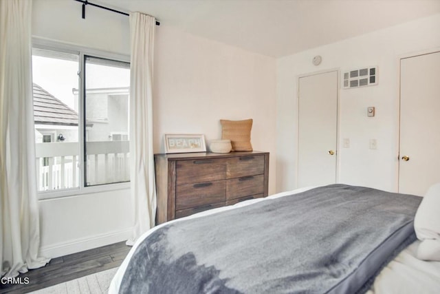 bedroom featuring baseboards, wood finished floors, and multiple windows