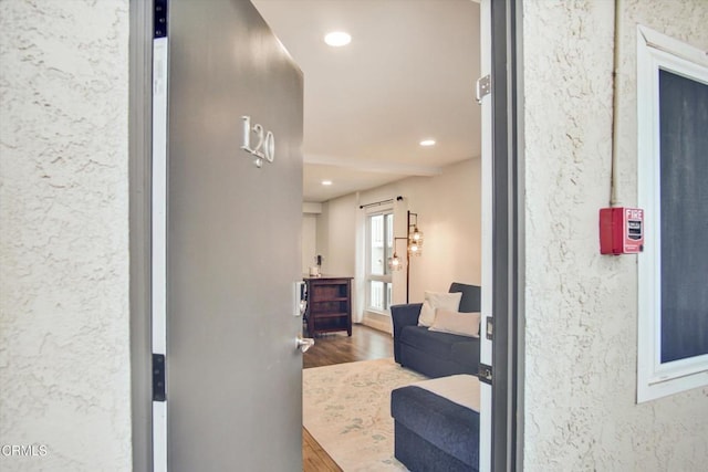 hallway featuring a textured wall, recessed lighting, and wood finished floors