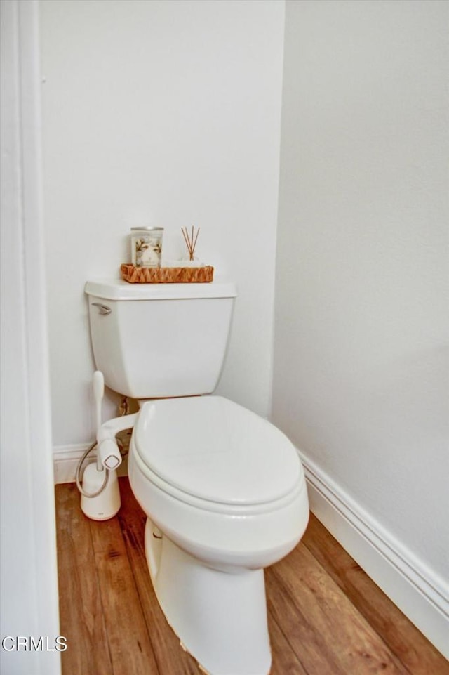 bathroom with toilet, baseboards, and wood finished floors