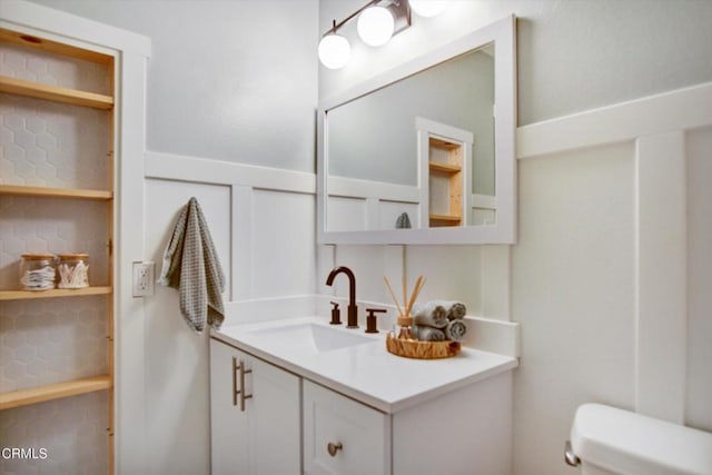 bathroom featuring vanity, a wainscoted wall, and toilet