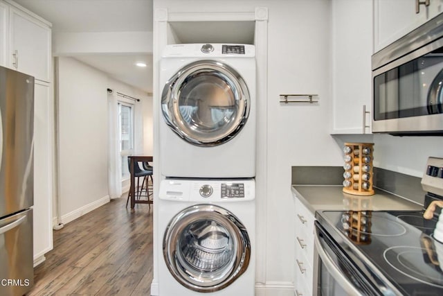 laundry area with laundry area, stacked washer and dryer, wood finished floors, baseboards, and recessed lighting