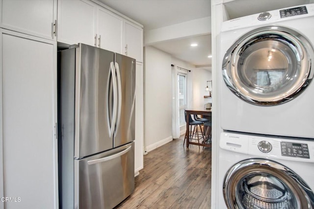 clothes washing area featuring recessed lighting, baseboards, stacked washing maching and dryer, and wood finished floors