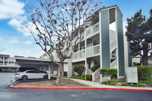view of building exterior with covered and uncovered parking