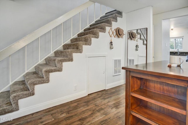 staircase featuring baseboards, visible vents, and wood finished floors
