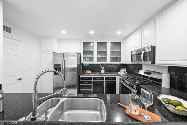 1930 S Beverly Glen Blvd Unit 103, Los Angeles, CA 90025 - kitchen with stainless steel appliances, a sink, white cabinets, dark stone counters, and tasteful backsplash