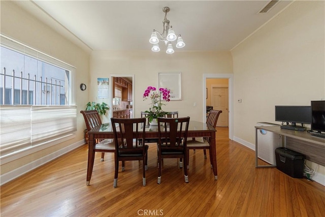 dining room featuring a chandelier, light wood-type flooring, visible vents, and baseboards